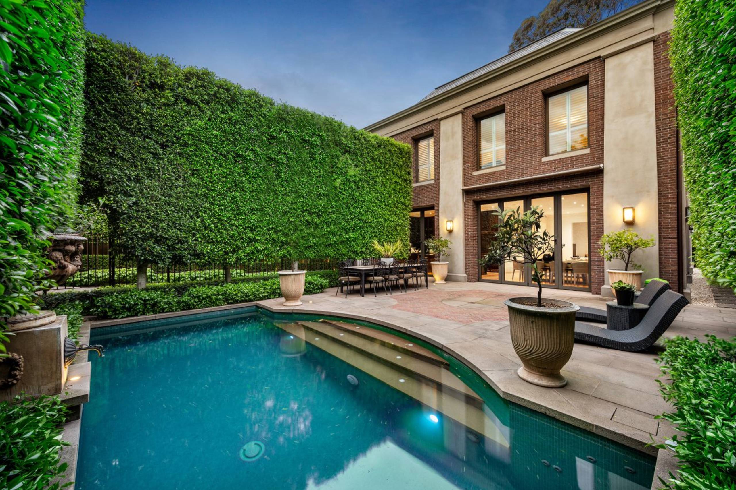 Luxury backyard pool and patio with hedges